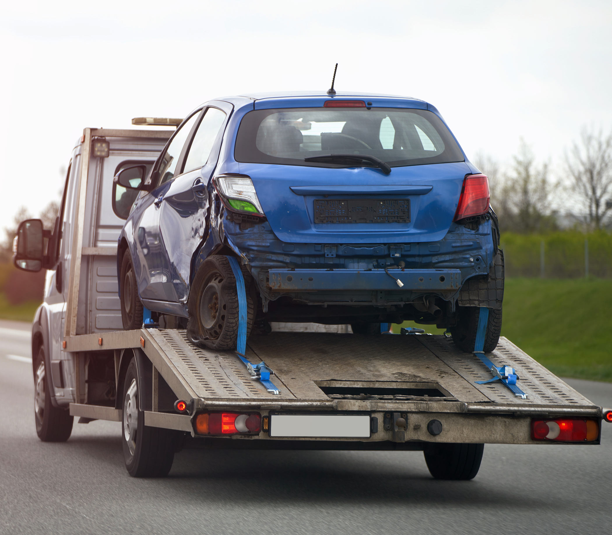 blue-car-trailer-is-being-towed-by-tow-truck